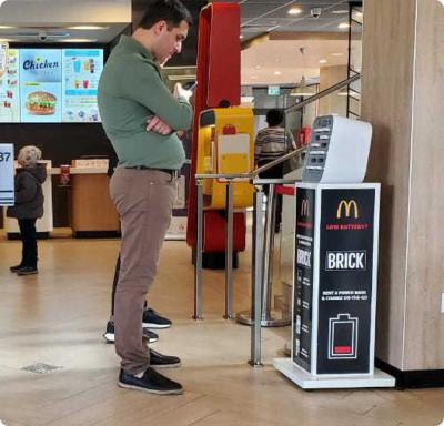 En Brickstation på McDonald's i Mcdonald's färger, med en kund som vill hyra powerbanks